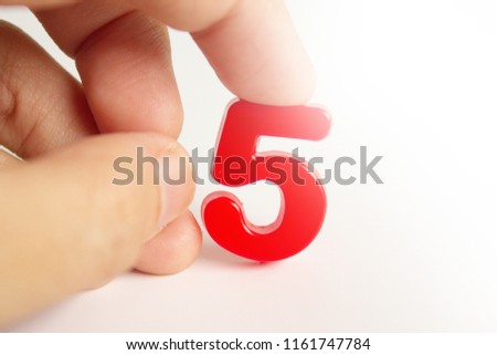 An index pressing on a magnetic plastic number five over a white background.
