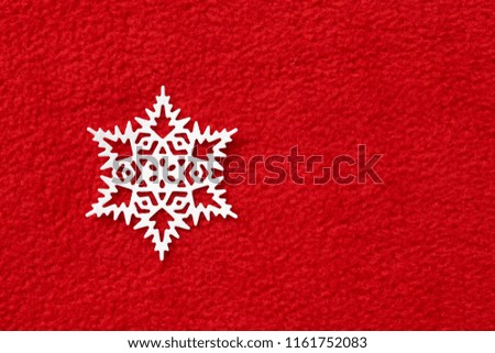 white paper snowflake on red fleece background
