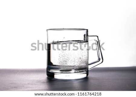effervescent tablets soluble in water in a transparent cup on a white background.