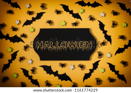 Decorative spiders, asterisks and halloween bats are arranged on an orange background. In the center is a black sign with the inscription Halloween. A vivid photo with a vignette.