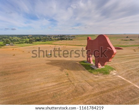 Statue in the form of an animal Bison on the Belarusian land against a background of grass, field and a blue sky Grodno region, Belarusю