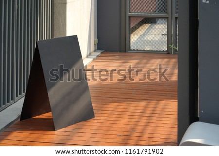 Simple black metal triangle for signage on the timber floor with natural sun light