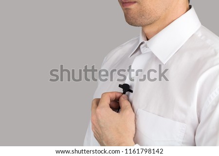 A man puts on lavalier microphone, interview, isolated on gray