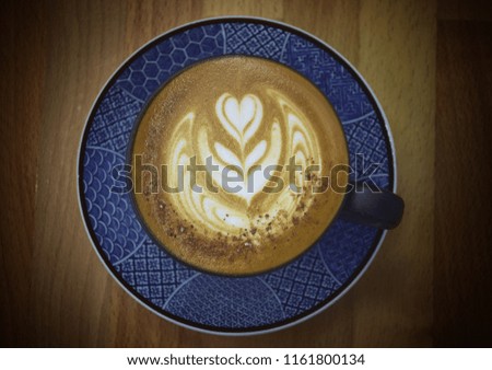 Good morning coffee , beautiful milk foam decoration in cappuccino blue coffee mug,top view and close up