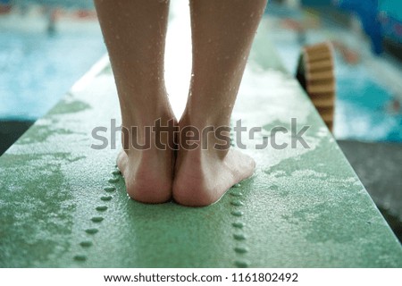 
feet of a young athlete on a springboard in the pool