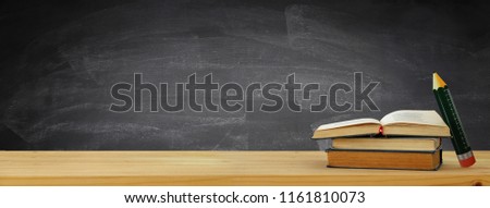 back to school banner. stack of books over wooden desk in front of blackboard