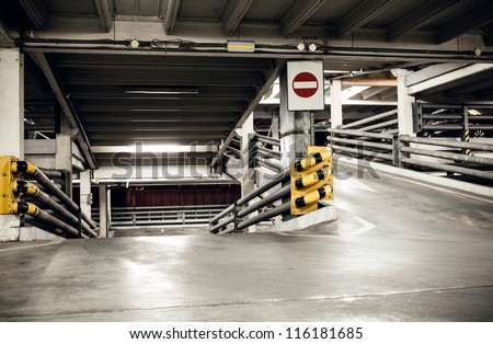 Parking garage in basement, underground interior and stop sign, construction technology steel and concrete Neon light in bright industrial building.