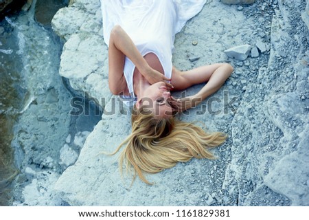 Beautiful blonde lying on the rocks, on the beach. Basking in the sun. Atmosphere of relaxation