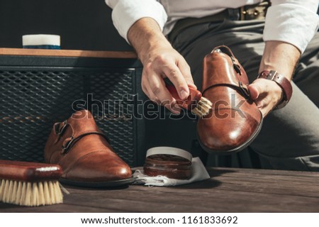 Man applies shoe polish with a small brush Royalty-Free Stock Photo #1161833692