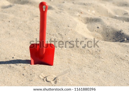 Red plastic shovel in yellow sand