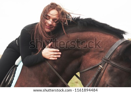 Young cute girl hugging her horse while sitting astride. She likes animals. Royalty-Free Stock Photo #1161894484