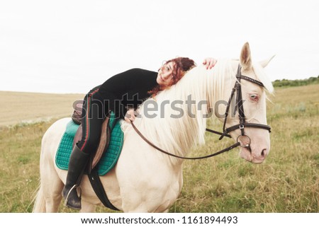 Young cute girl hugging her horse while sitting astride. She likes animals. Royalty-Free Stock Photo #1161894493