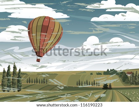 Red hot air balloon and green rural meadow on a blue cloudy sky