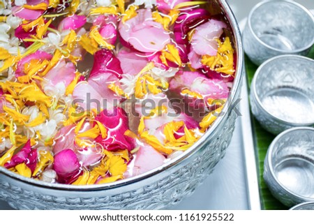 Songkran festival concept with fresh jasmine, rose, Marigold and various colorful flowers in silver bowl with water on family day.