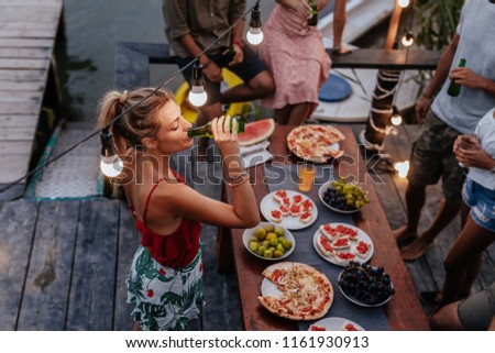 Group of young people having outdoor dinner party by the river.