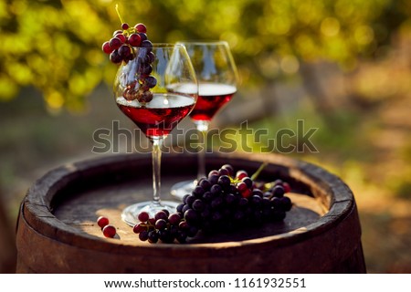 Two glasses of red wine with a bottle on a wooden barrel Royalty-Free Stock Photo #1161932551