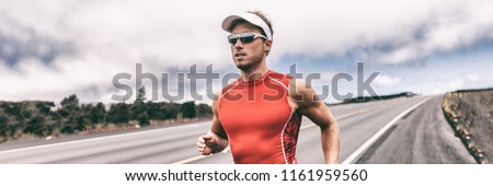 Triathlon runner man running on road panoramic backbround. Fit athlete jogging on competition race. Triathlete training for marathon banner panorama.