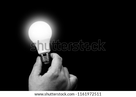 Holding opened light bulb in the dark background, black and white picture tone 