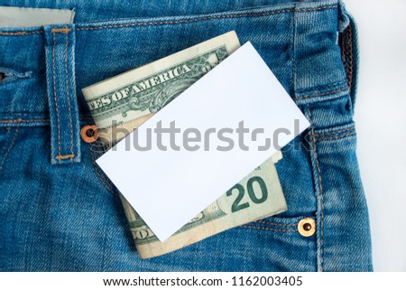Blank card and cash are lying in a pocket of blue jeans.