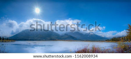 Our star , the sun sparkles brightly - sunburst image - Preventing the lake from freezing completely. The brilliantly lit up clouds, blue sky ,snowy alps & the lovely fall foliage add a unique charm.