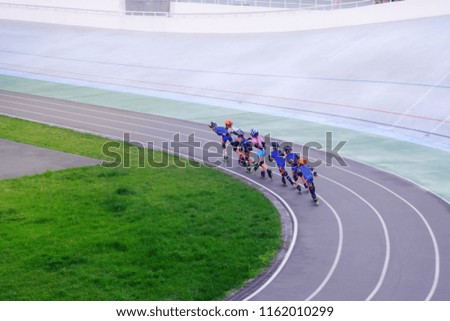 children on rollers in helmets and blue sports suits ride on a racing platform for athletes, sports and recreation

