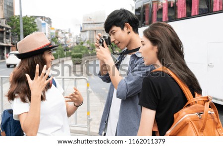 Young man is taking a photo of his friends at the street in Thailand