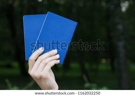 blue cover passport documents in hand on dark blurred unfocused natural background with empty space for copy or text