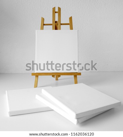 Wooden easel and four empty white linen canvas for drawing