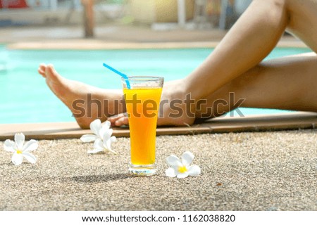 Beautiful  legs. Close-up of female legs and cocktail with a swimming pool on the background