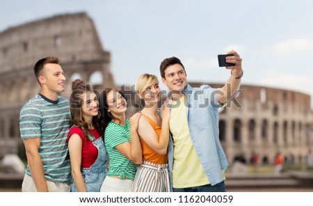 travel, tourism and technology concept - group of happy smiling friends taking selfie by smartphone over coliseum background