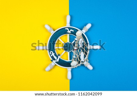 The sea steering wheel on a yellow and blue background. Top view travel or vacation concept. Summer background. Flat lay photo, top view
