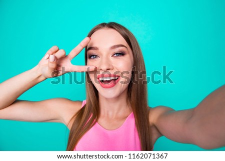 Self-portrait of young straight-haired gorgeous nice cute attractive perfect smiling girl, showing v-sign. Isolated over bright vivid turquoise background
