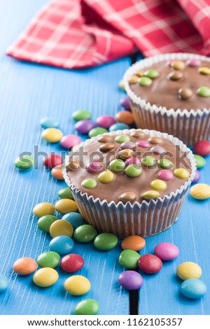 Sweet cupcakes with candies on blue table.
