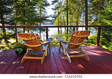Wooden deck at forest cottage with Adirondack chairs Royalty-Free Stock Photo #116210701