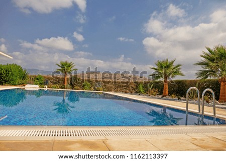 Large pool on the background of expensive villas and palm trees 