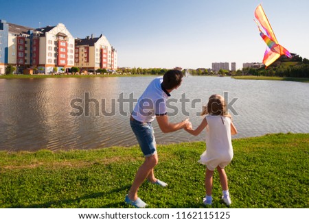 Beautiful dad and daughter play with kite, has fun happy emotions. Portrait in city landscape. Family kids style. Amazing love couple. Children and adult hobby. 