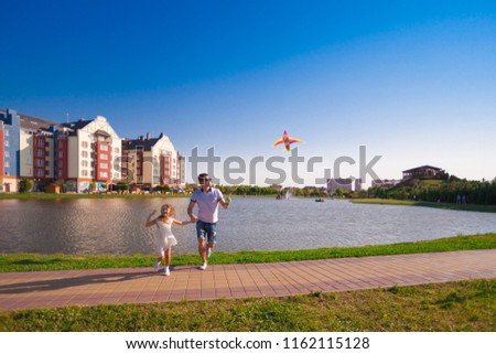 Beautiful dad and daughter play with kite, has fun happy emotions. Portrait in city landscape. Family kids style. Amazing love couple. Children and adult hobby. 