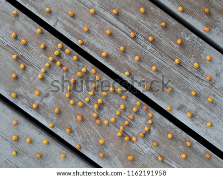 Word "food" is shaped of sea buckthorn berries scattered on the deck. Orange berries on the stuck diagonal boards.