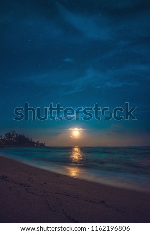 Night Scene - A full moon rises with stars over the Pacific Ocean at Lydgate Beach, just south of Wailua on the island of Kauai, Hawaii, USA.