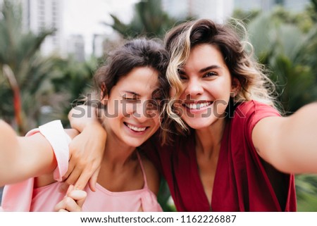 Stunning white woman with sincere smile making selfie with best friend. Outdoor portrait of blissful sisters spending weekend together.