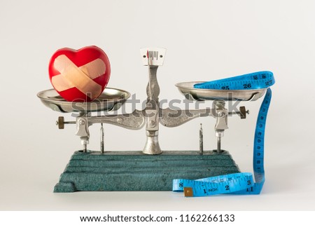 Heart injury model and blue tape measure in pan weight scale on white background.Dieting and health care concept.