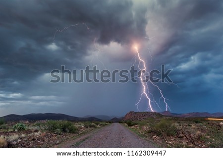 Safford, Arizona - Positive cloud to ground lightning bolt shooting out behind a beautiful storm at sunset.