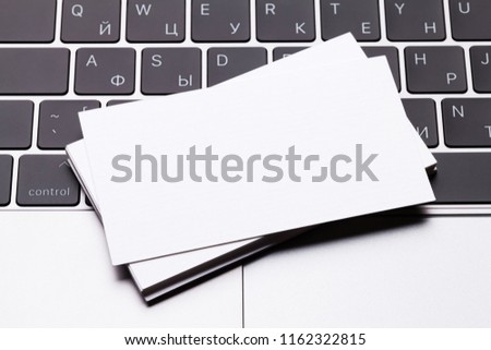 Blank business cards over laptop keyboard. Top view with space for your text