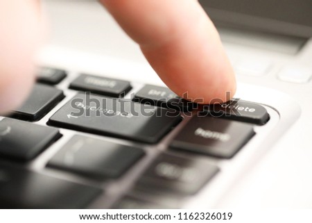 finger pushing the delete button tab on a computer laptop keyboard. Concept of erasure or extermination. Getting rid of. Dispose and cover history. Erasing the past. 