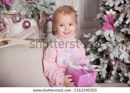 Happy little girl with toys at home sitting near Christmas tree. Happy Family consept.
