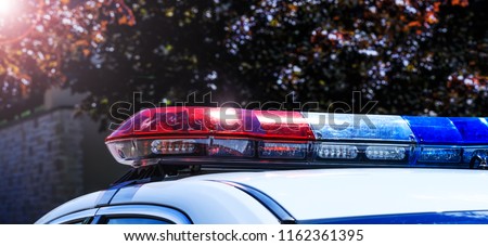 Police lights on car during traffic surveillance on the city road. Flash light on the vehicle of the Emergency Services. Red and blue flashes on the cars of the Patrol specialized unity. 