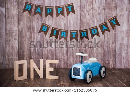 Blue wooden toy car on a wooden background. Decorative zone The first year.