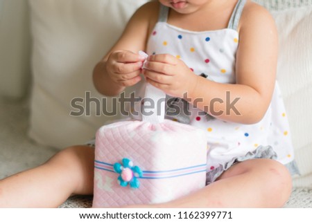 Asian little child hands pulling white tissue paper from tissue box