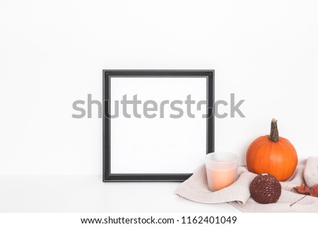 Autumn composition. Photo frame, pumpkins, candles, dried leaves on white background. Autumn, fall, halloween concept. Front view, copy space, square