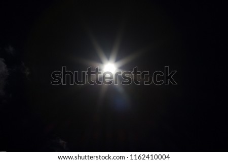 An underexposed shot of the sun at noon - sunbeams and flairs Royalty-Free Stock Photo #1162410004